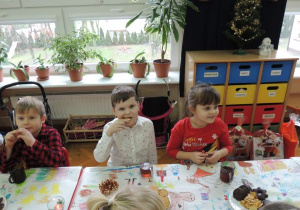 podczas poczęstunku dzieci siedzą przy stolikach przykrytych papierowymi obrusami ozdobionymi przez dzieci
